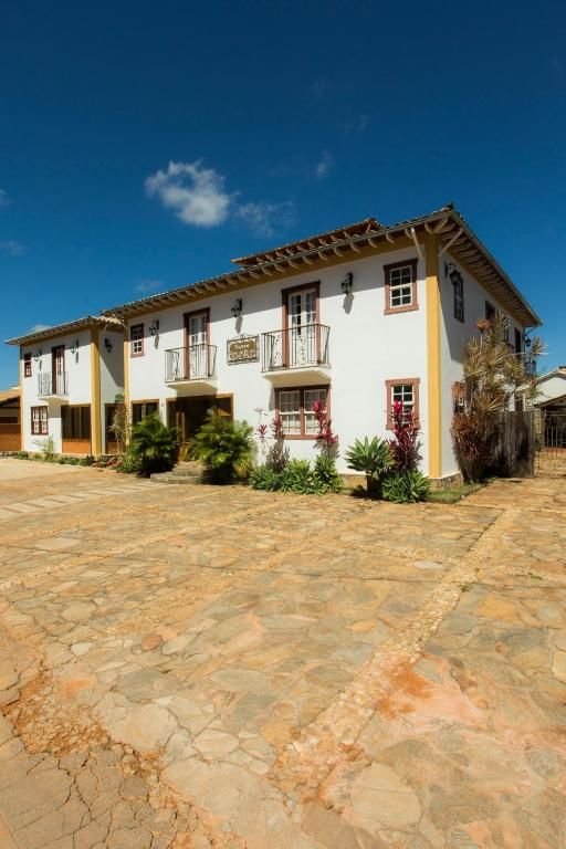 Fachada colonial branca da pousada com pátio de pedra